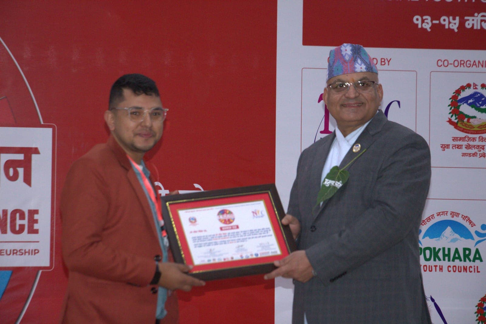 Rabin Paudel receiving a framed Icon of Gandaki certificate from Chief Minister Surendra Raj Pandey on the Provincial Youth Conference stage